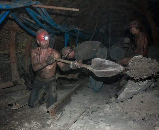 Miners working in difficult conditions underground with high exposure to coal dust.